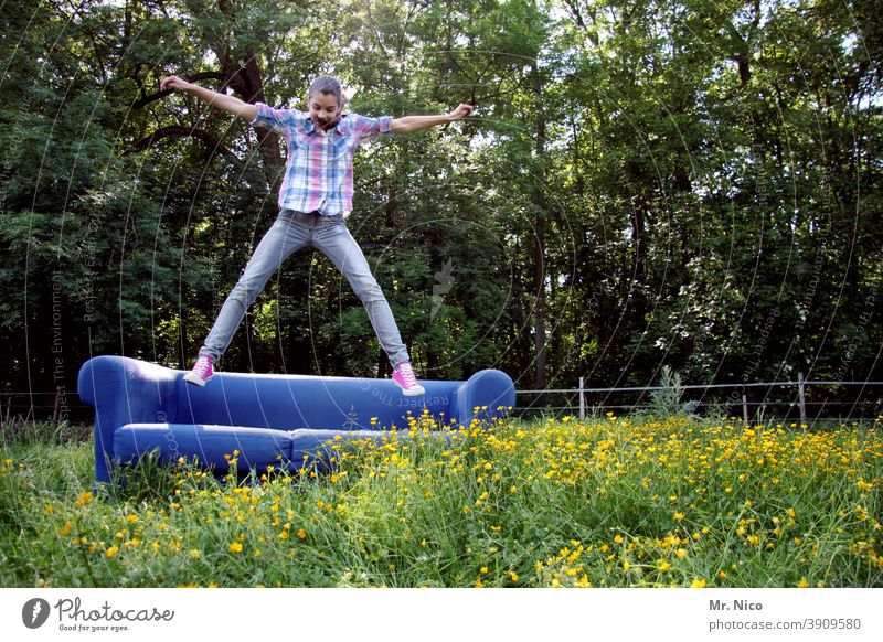 Junges Mädchen hüpft auf einem blauem Sofa welches auf einer grünen Wiese steht Umwelt Natur Gras natürlich Idylle Blumenwiese Wildpflanze Sommer hüpfen