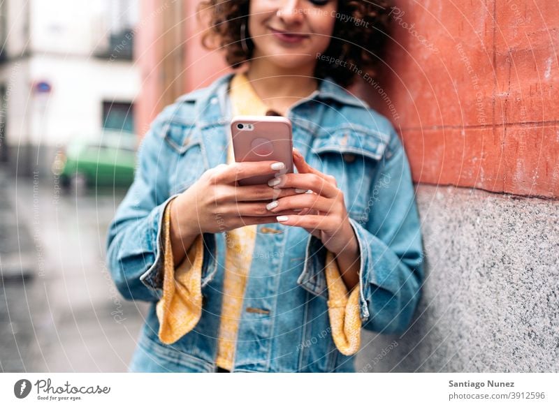 Junge Frau mit Telefon Kaukasier krause Haare unerkannt gesichtslos jung per Telefon Straße Stadtleben Lächeln Glück Funktelefon Smartphone benutzend Mitteilung