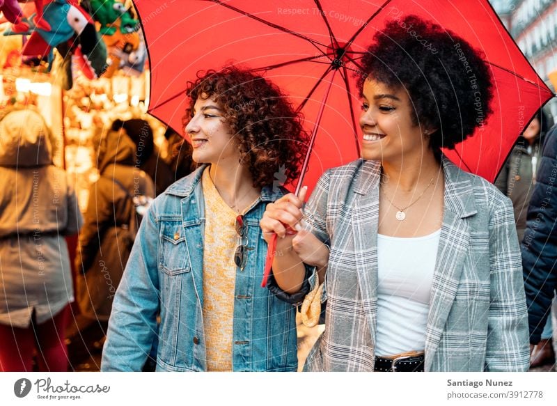 Fröhliche Freunde im Regentag Regenschirm Afro-Mädchen schwarze Frau Kaukasier Stadtleben Lächeln Vorderansicht Porträt Frauen Blick Straße multiethnisch