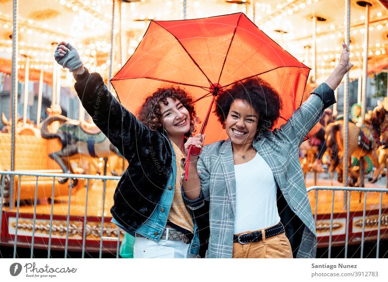 Fröhliche Freunde an einem regnerischen Tag Regenschirm Regentag Afro-Mädchen schwarze Frau Kaukasier Stadtleben Lächeln Vorderansicht Porträt Frauen