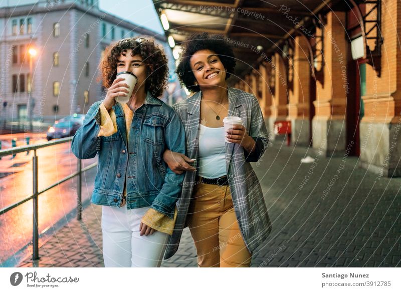 Afro Mädchen und Freund in Straße Tasse Kaffee laufen Freunde trinken in die Kamera schauen Frauen multiethnisch Afro-Mädchen Kaukasier Porträt Spaß haben