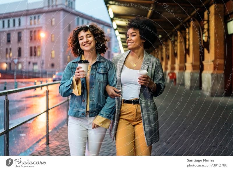 Afro Mädchen und Freund in Straße Tasse Kaffee laufen Freunde trinken Frauen multiethnisch Afro-Mädchen Kaukasier Porträt Spaß haben Vorderansicht Freundschaft