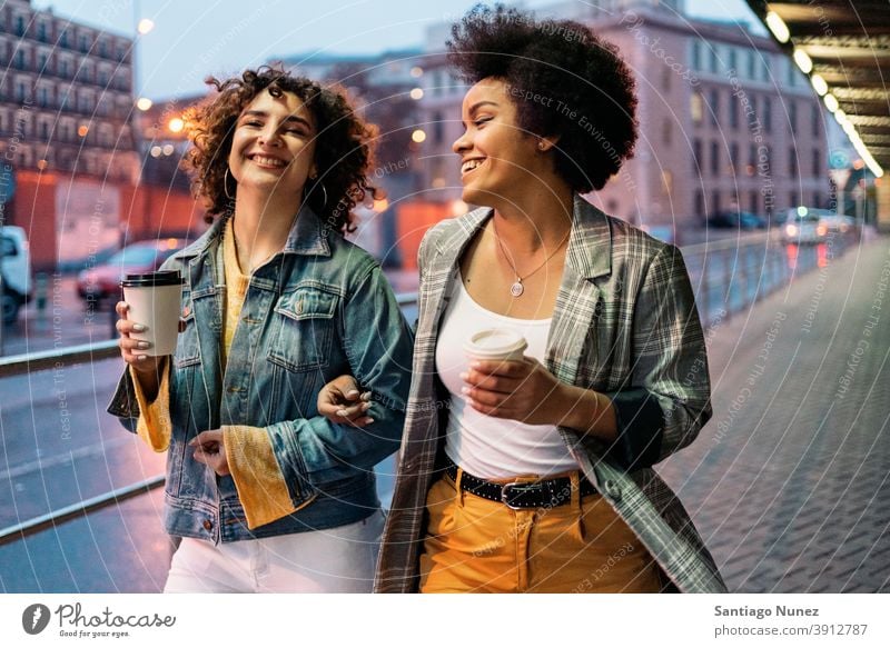 Afro Girl und Freund haben Spaß Tasse Kaffee laufen Straße Freunde trinken Frauen multiethnisch Afro-Mädchen Kaukasier Porträt Spaß haben Vorderansicht