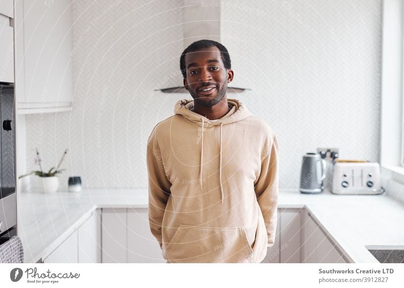 Porträt eines lächelnden jungen Mannes, der in der Küche eines neuen Hauses steht junge Männer Hauskauf heimwärts neues Zuhause erste Wohnung Einzug Umzugstag