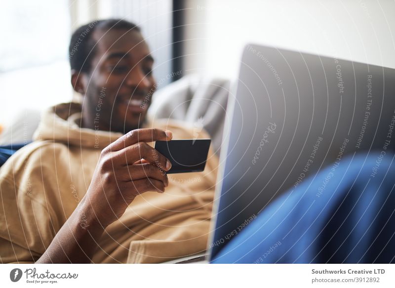 Junger Mann zu Hause liegend auf Sofa mit Laptop mit Kreditkarte zum Online-Shopping Lügen räkeln Computer Debitkarte Auszahlungstag Technologie