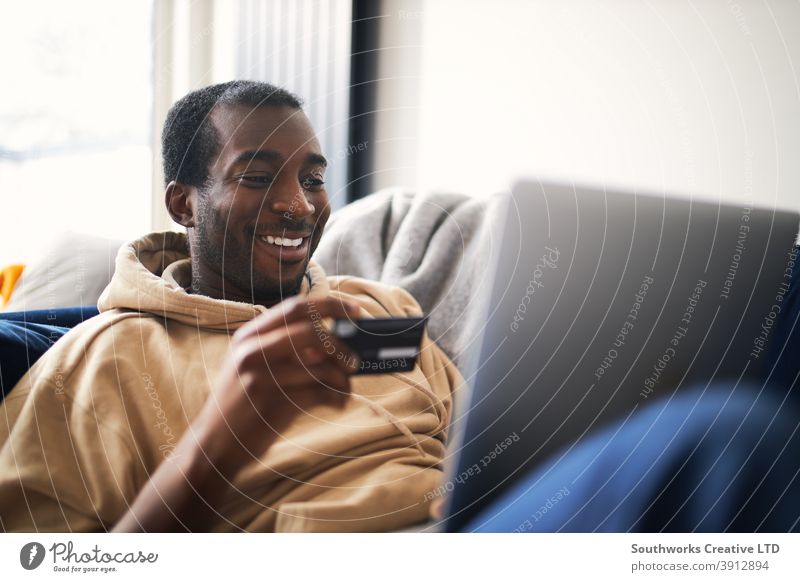 Junger Mann zu Hause liegend auf Sofa mit Laptop mit Kreditkarte zum Online-Shopping Lügen räkeln Computer Debitkarte Auszahlungstag Technologie