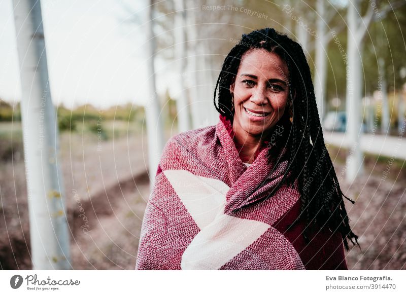 Porträt von hispanischen Mitte erwachsene Frau im Freien halten in Decke eingewickelt. Herbstzeit Afrofrau Latein Sonnenuntergang Natur Hut Lächeln Glück