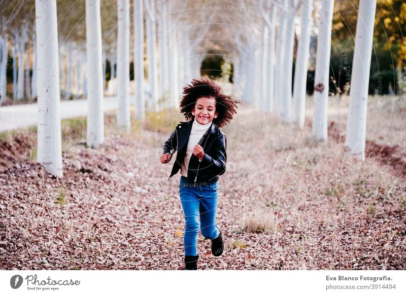 Porträt von niedlichen afro Kind Mädchen läuft bei Sonnenuntergang während der goldenen Stunde, Herbstzeit, schöne Bäume Hintergrund rennen Spaß Afro-Look Natur
