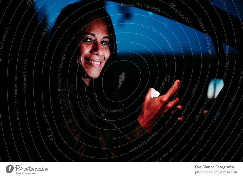 hispanische Frau mit Mobiltelefon im Auto bei Nacht. Reisen und Technologie Konzept Handy PKW Bildschirm reisen schön mittlerer Erwachsener Lebensstile klug