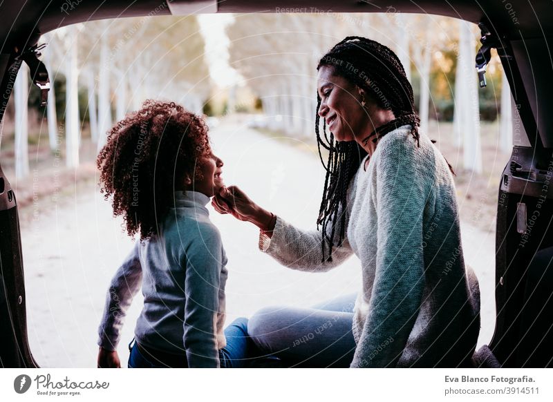 hispanische Mutter und Afrokindermädchen sitzen in einem Auto in der Natur. Herbstsaison. Familien- und Reisekonzept Porträt Tochter im Freien gemischte Rasse