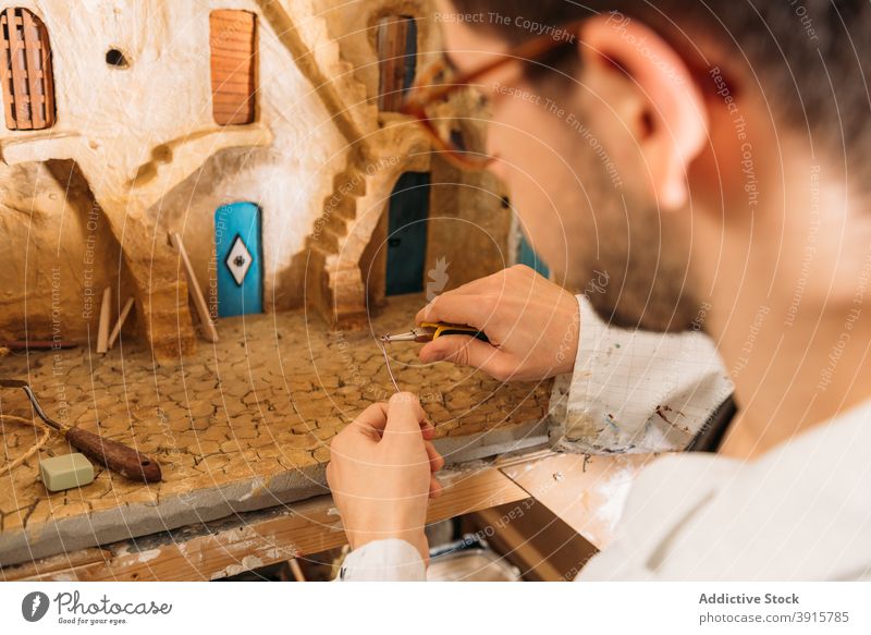 Kunsthandwerker beim Erstellen eines Modells eines Lehmhauses im Atelier Ton Werkstatt Mann Gebäude Haus Miniatur Kunstgewerbler kreieren Tür männlich Hobby