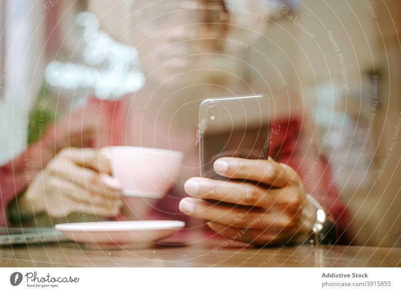 Schwarzer Mann benutzt Smartphone im Café Kälte Browsen Kaffee sich[Akk] entspannen Wochenende trinken Kaffeehaus männlich ethnisch schwarz Afroamerikaner Tisch