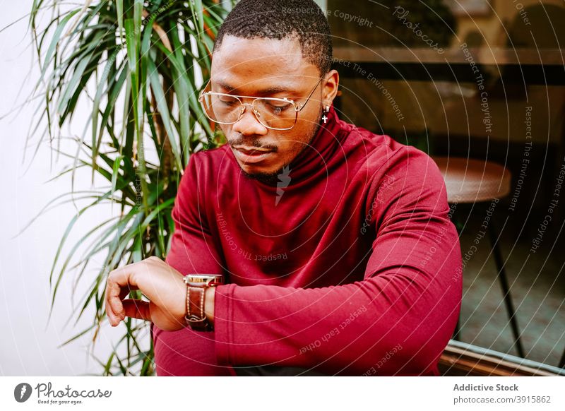 Schwarzer Mann überprüft Armbanduhr in der Stadt prüfen Zeit warten Zeitmanagement Accessoire Genauigkeit Großstadt punktuell männlich ethnisch schwarz