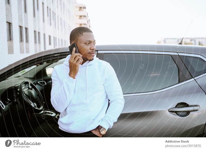 Schwarzer Mann durchsucht Smartphone in der Nähe des Autos Browsen PKW geparkt Surfen soziale Netzwerke Internet männlich ethnisch schwarz Afroamerikaner reich