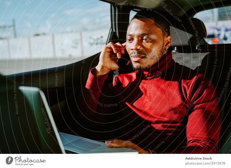 Männlicher Unternehmer arbeitet am Laptop im Auto Geschäftsmann Arbeit PKW multitask Mann reich Reichtum Erfolg männlich schwarz ethnisch Afroamerikaner