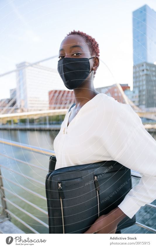 Schwarze Geschäftsfrau in Schutzmaske auf Stadtstraße Mundschutz behüten urban selbstbewusst Stil modern Großstadt Coronavirus Pandemie jung schwarz
