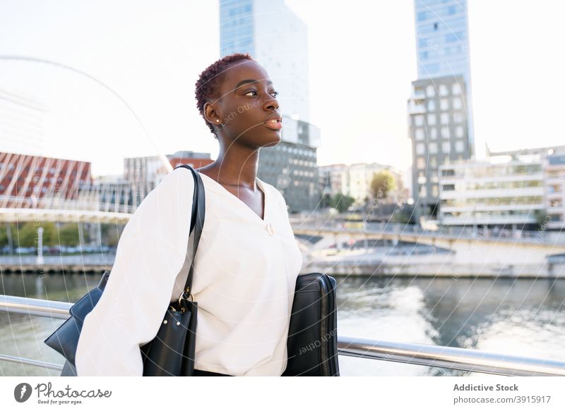 Afroamerikanische Geschäftsfrau stehend auf Stadtböschung selbstbewusst positiv modern urban Stil Erfolg Glück jung Großstadt schwarz Afroamerikaner ethnisch