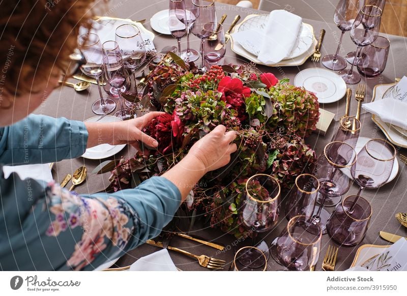 Anonyme Frau deckt Tisch mit Blumen zu Hause Tabelleneinstellung Einstellung heimwärts festlich Veranstaltung Hausfrau geblümt Dekor Blütezeit Anlass