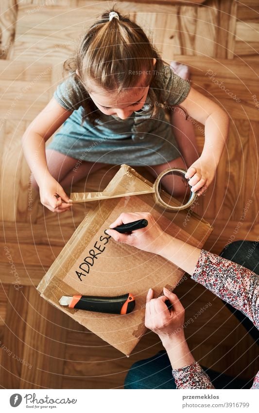 Frau schreibt eine Adresse auf ein Karton-Paket, das zum Versand vorbereitet wird Ansicht Stock Geschenk Auspacken Klebeband Mädchen Tochter Füller schäumen