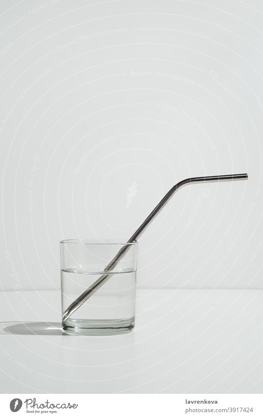 Transparentes Wasserglas auf Weiß mit nachhaltigem Metallstrohhalm Glas trinken Stroh umweltfreundlich Getränk cool kalt Gesundheit durstig Frische Bestandteil