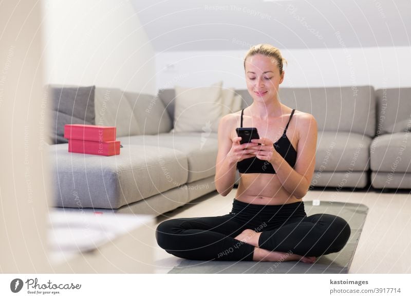 Schöne blonde Frau beim Heimtraining in der Halle. Frau praktiziert Yoga zu Hause. Fitness-Lehrgänge für einen gesunden, aktiven Lebensstil für Mädchen. Frau nutzt Quarantäne für Heimtraining.