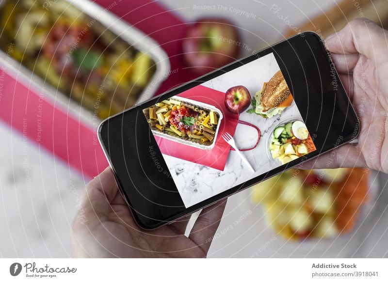 Person, die ein Foto von Essen zum Mitnehmen macht Food-Fotografie Imbissbude Smartphone Lunch-Box fotografieren Spätzle Salatbeilage Belegtes Brot Apfel