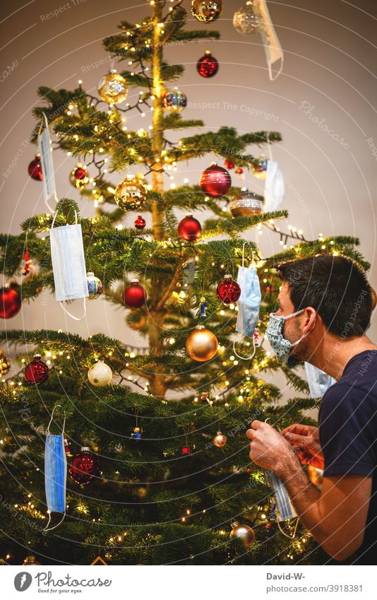 Corona - der Weihnachtsbaum wird geschmückt schmücken Christbaum Christbaumschmuck Maske Mundschutz Mann weihnachtsdekoration Pandemie schützen Coronavirus