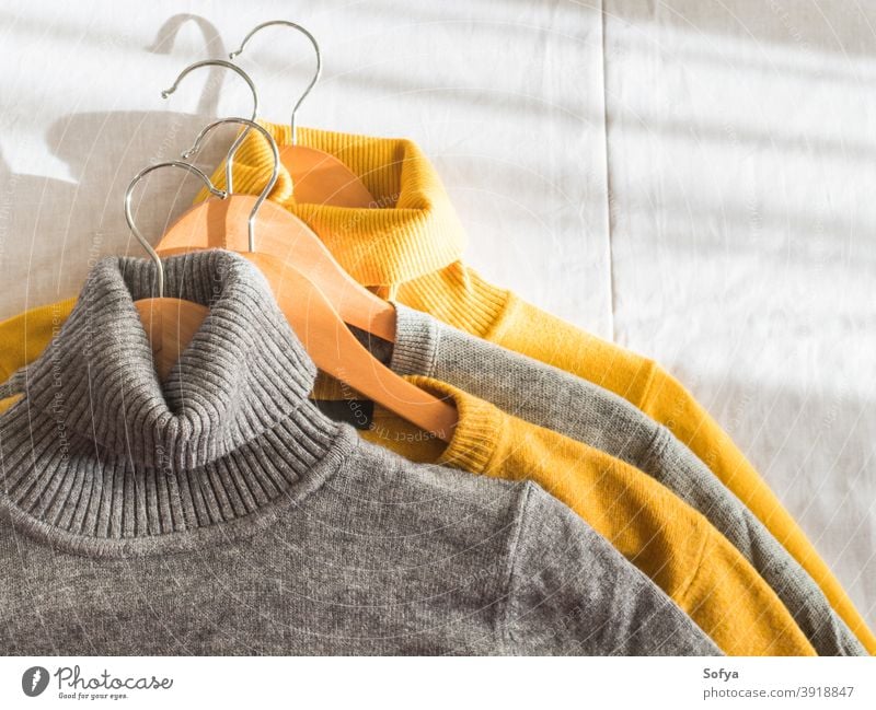 Gelbe Leuchtfarbe und graue Winterpullover Pullover gelb Herbst Kleiderbügel Kaschmiri fallen beleuchtet Hintergrund stricken gemütlich Mode warm Farbe