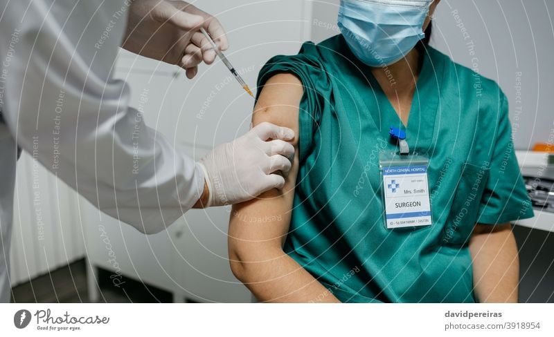 Nicht erkennbare Chirurgin erhält Coronavirus-Impfstoff Gesundheitspersonal unkenntlich einspritzend Arzt Prioritätsgruppe covid-19 Nahaufnahme Arme Klinik