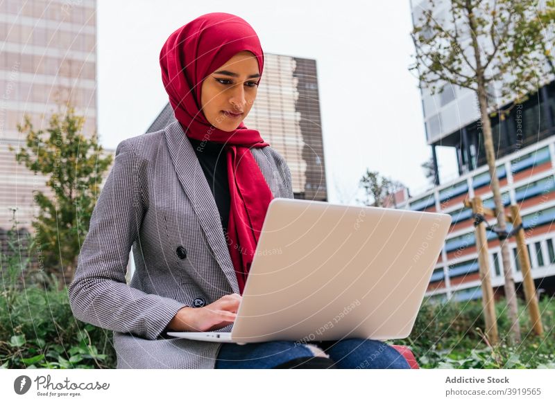 Ethnische weibliche Freiberufler in Hijab arbeiten am Laptop in der Stadt Frau freiberuflich Arbeit Großstadt Unternehmer Kopftuch Straße Geschäftsfrau ethnisch