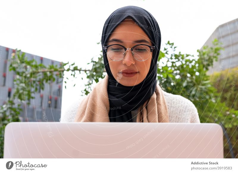 Ethnische weibliche Freiberufler in Hijab arbeiten am Laptop in der Stadt Frau freiberuflich Arbeit Großstadt Unternehmer Kopftuch Straße Geschäftsfrau ethnisch