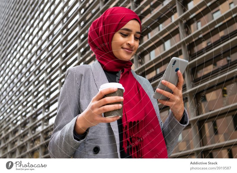 Glückliche ethnische Frau in Hijab Surfen Smartphone auf der Straße Browsen Tradition muslimisch Imbissbude Kaffee Nachricht Großstadt arabisch