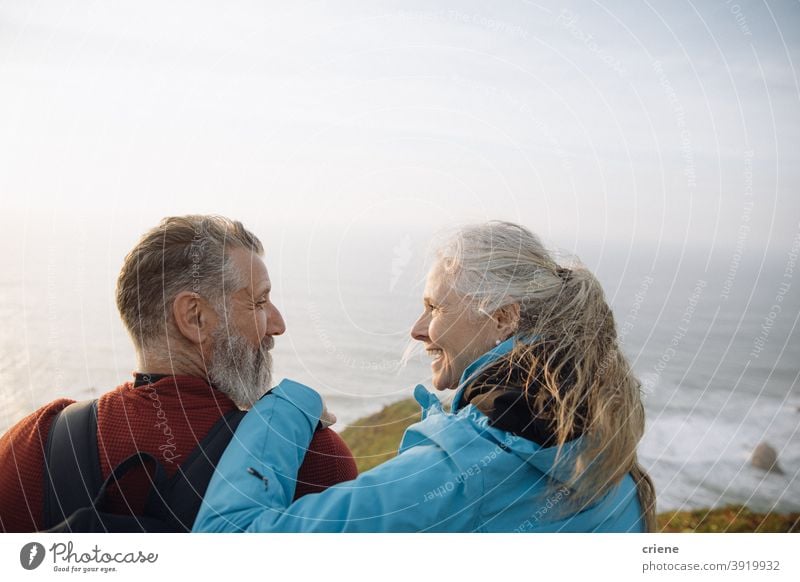 kaukasischen Senior Paar sitzt auf Klippe genießen Sonnenuntergang zusammen schauen sich an Frau Glück alt älter Liebe Lächeln Menschen Familie reif Ruhestand