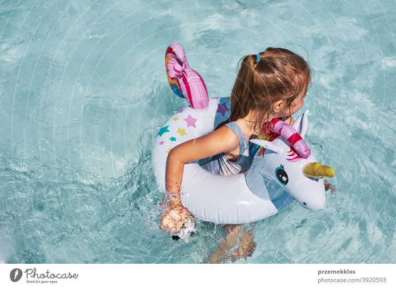 Kleines Mädchen spielt in einem Schwimmbad mit aufblasbaren Ring Spielzeug in Form von Einhorn authentisch Hinterhof Kindheit Familie Spaß Fröhlichkeit Glück