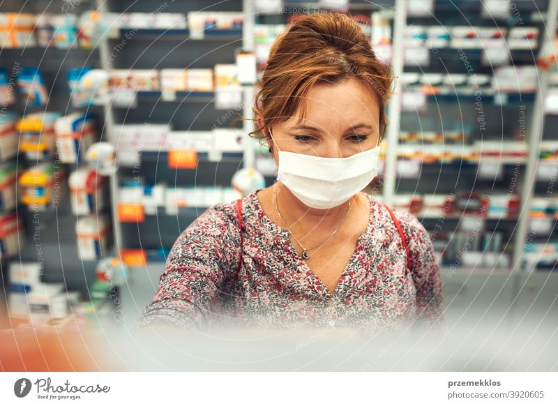 Frau kauft in der Apotheke ein, kauft Medikamente, trägt Gesichtsmaske während des Ausbruchs des pandemischen Coronavirus Chemiker Werkstatt Mundschutz covid-19
