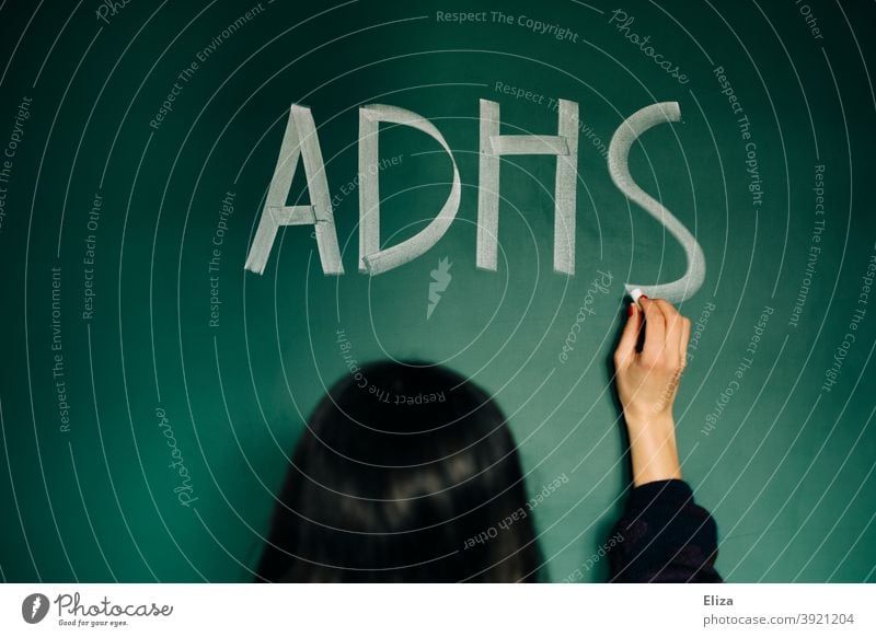 Eine junge Frau schreibt ADHS auf eine Tafel Störung Krankheit Aufmerksamkeitsdefizit Diagnose ADS Hyperaktivität