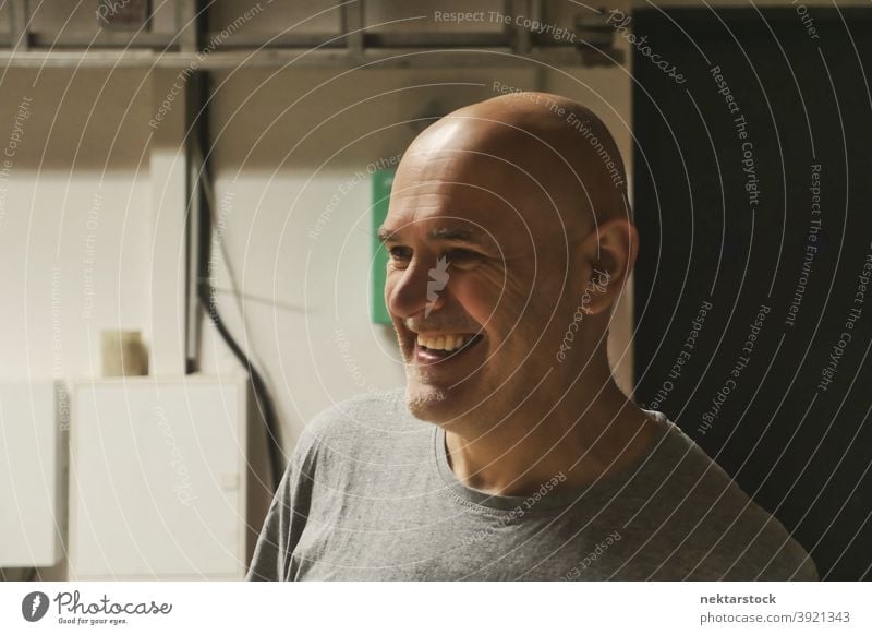 Kahlköpfiger Mann lächelnd in Garage Hintergrund kahl Kaukasier Arbeiter Werkstatt diy keine Haare 1 Mensch Handarbeit industriell Maschinenhalle Industrie
