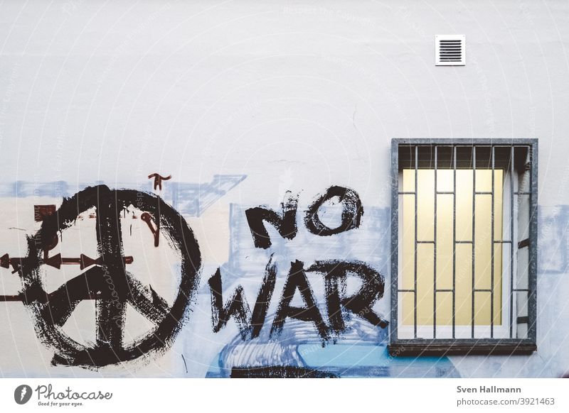 Graffiti an Wand mit Fenster Peace krieg frieden no war Krieg Frieden Gitter vergittert Gewalt grau Außenaufnahme Mauer Schriftzeichen Farbfoto Menschenleer