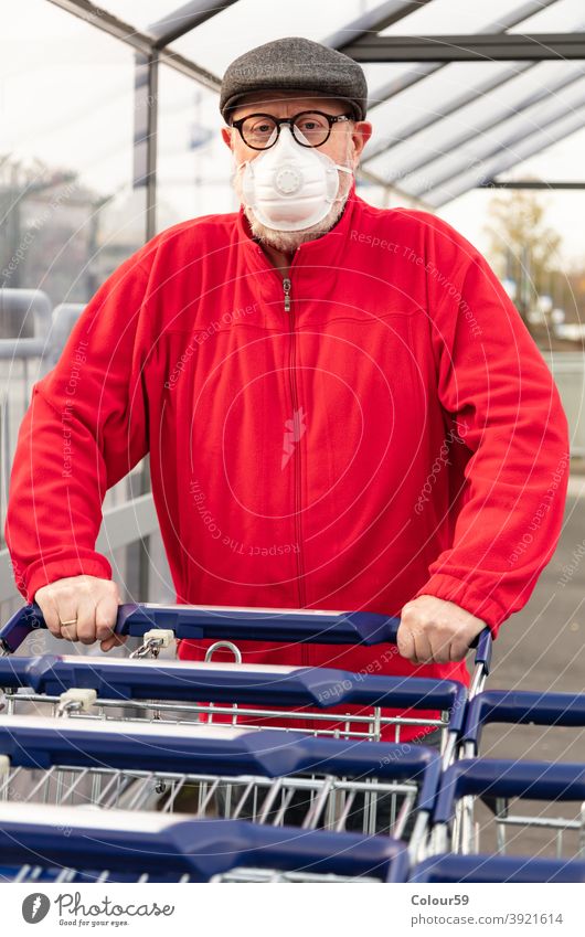 Mann trägt eine Maske beim Schieben eines Einkaufswagens neue Normale Opa COVID epidemische Gesichtsmaske 2019-ncov schützend Infektion Käufer Nur ein Mann