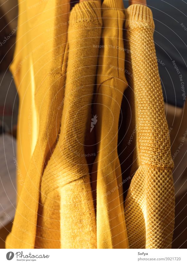 Gelbe Leuchtfarbe Winterpullover auf Kleiderbügeln Pullover gelb Herbst Kaschmiri fallen beleuchtet Hintergrund stricken gemütlich Mode warm Farbe Strickwaren