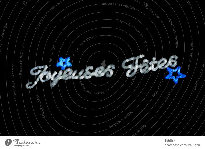 Text Joyeuses Fetes und blaue Sterne unscharf mit Bokeh Weihnachtsbeleuchtung text Joyeuses fetes Unschärfe silber Licht schwarzer hintergrund blendenflecken