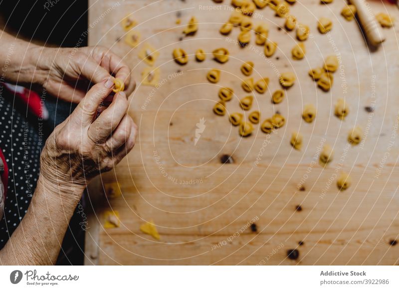 Ältere Frau bereitet Tortellini in häuslicher Küche zu Koch Italienische Küche selbstgemacht Tradition Knödel vorbereiten Lebensmittel gealtert Teigwaren roh