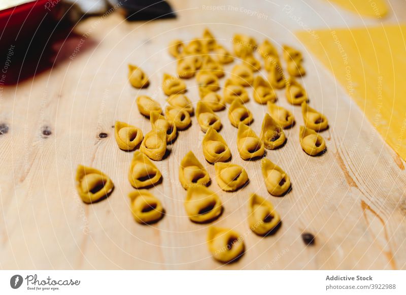 Traditionelle rohe Tortellini auf Holztisch in der Küche Italienische Küche Knödel selbstgemacht Lebensmittel heimisch ungekocht Teigwaren Gebäck