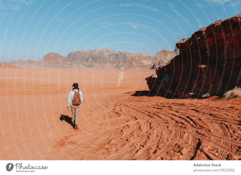 Anonymer Reisender stehend in Wüste mit Bergen während des Urlaubs wüst Sandstein Tal erkunden Tourist trocken trocknen Natur Fernweh Wadi Rum Jordanien