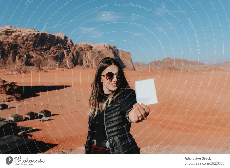 Fröhliche Frau stehend mit Sofortbild in der Wüste sofort Foto wüst Reisender heiter altmodisch Sandstein Tal Gedächtnis Wadi Rum Jordanien Tourismus Urlaub