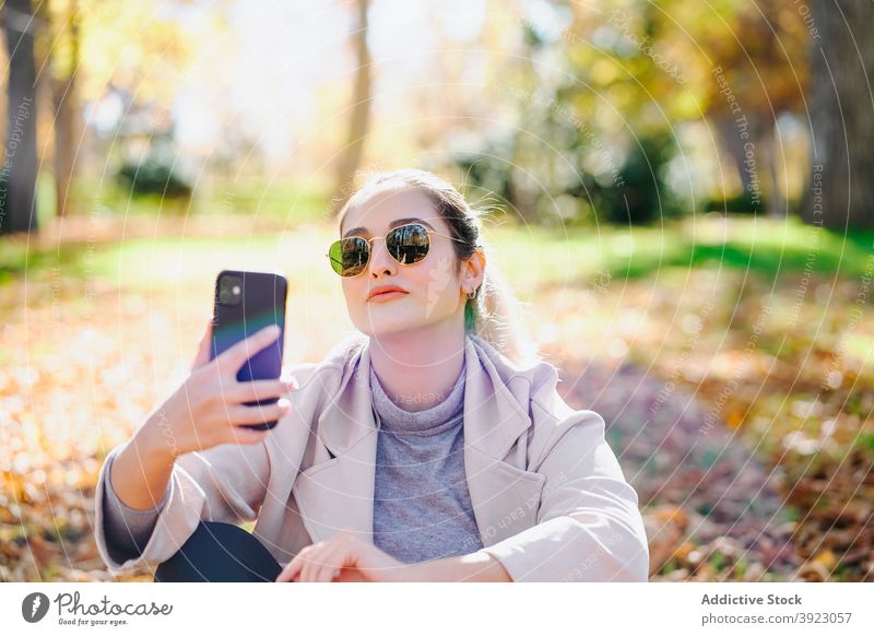 Positive Frau sendet Nachricht auf Handy im Park Smartphone genießen heiter Herbst Apparatur Inhalt Gerät Funktelefon Glück Optimist Dame froh Freude
