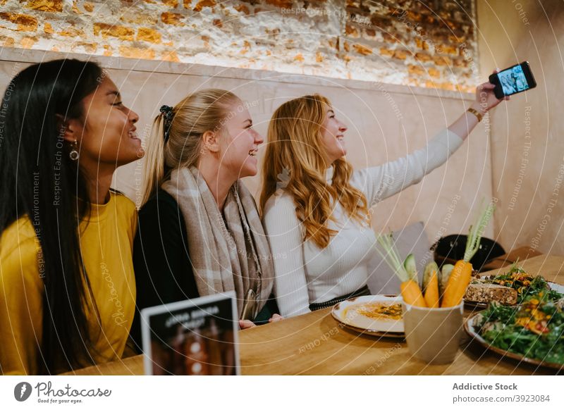 Gesellschaft von multiethnischen Frauen, die ein Selfie im Café machen Freund Menschengruppe Zusammensein Smartphone fotografieren heiter Freundschaft