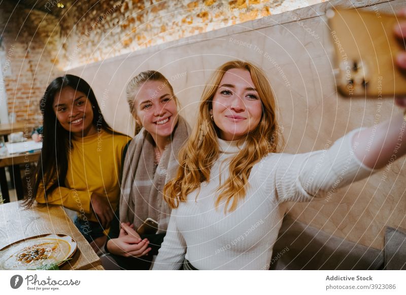 Gesellschaft von multiethnischen Frauen, die ein Selfie im Café machen Freund Menschengruppe Zusammensein Smartphone fotografieren heiter Freundschaft