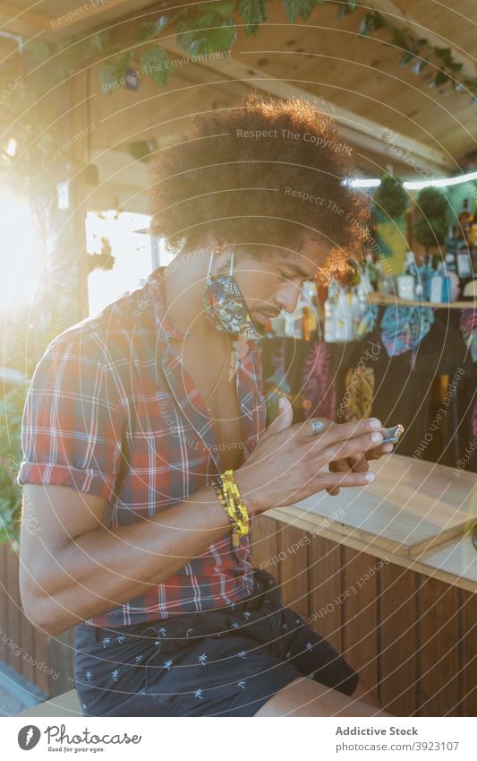 Mann benutzt Smartphone in Bar benutzend Telefon Mobile Browsen Nachricht Afroamerikaner Afro-Look schwarz ethnisch männlich krause Haare Surfen tropisch Gerät