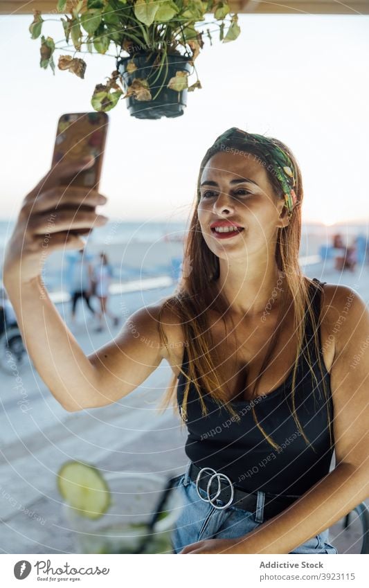 Glückliche Frau nimmt Selfie in Bar Smartphone benutzend Sommer tropisch unter heiter Browsen Telefon Nachricht Lifestyle Apparatur ruhen Gerät Optimist Lächeln